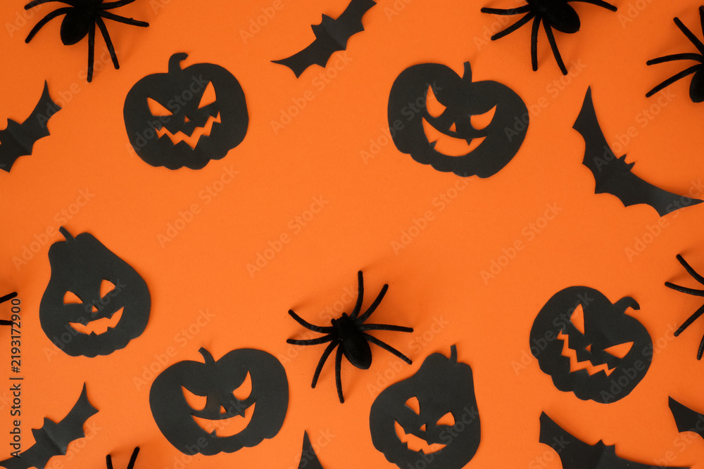 Obraz premium Black jack-o'-lanterns, spiders, bats shapes and place for text on an orange background