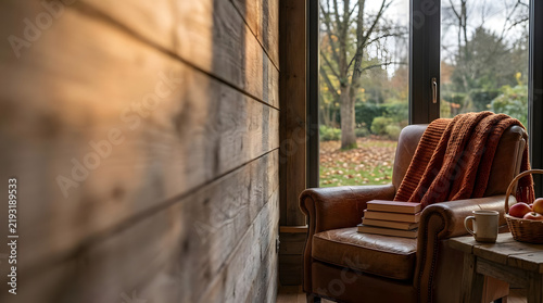 Armchair in rustic cabin looking out at autumn trees.