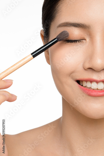 Fotografía Smiling Asian Woman Applying Eyeshadow with Makeup Brush