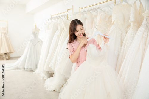 Happy Bride Choosing Wedding Dress in Bridal Boutique