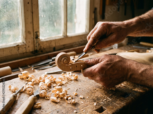 Violin Maker Hands Carving Wood Scroll with Chisel in Artisan Workshop Close-Up