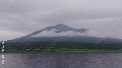 Flying over calm water to Rishiri Fuji mountain on island in Hokkaido, Japan