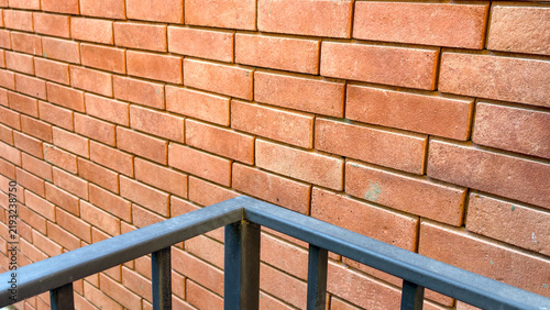 Fotografie Warm toned brick wall creating a textured background, with a dark metal railing