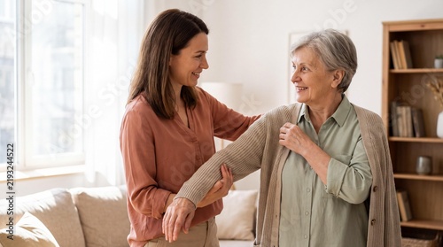 A caring daughter helps her elderly mother put on a cardigan, showing support and love in a warm, domestic setting.