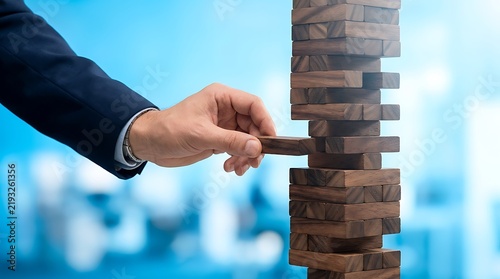 Risk management concept with businessman hand pulling wooden block from tower, business strategy and stability metaphor, precarious financial planning