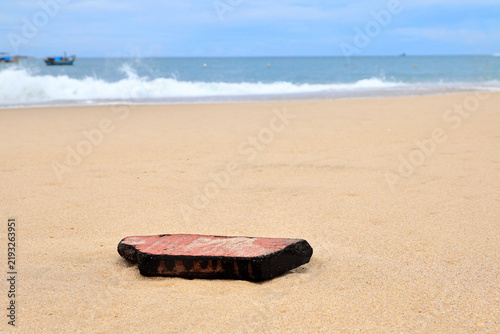 Фотография Red Brick Shard on Sandy Beach with Sea Horizon