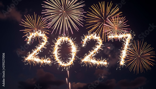 Happy new year 2027 text written with bright sparkling sparklers and fireworks in the night sky
