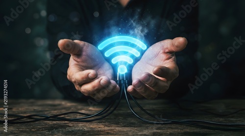 Hand holding glowing wireless connection symbol on dark background with technology concept