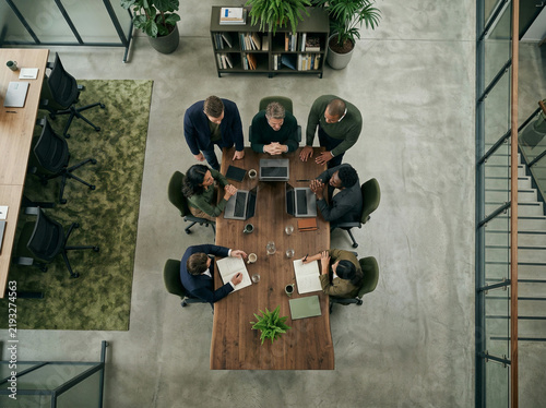 Seven colleagues gathered around a dark wood table in a modern bright office