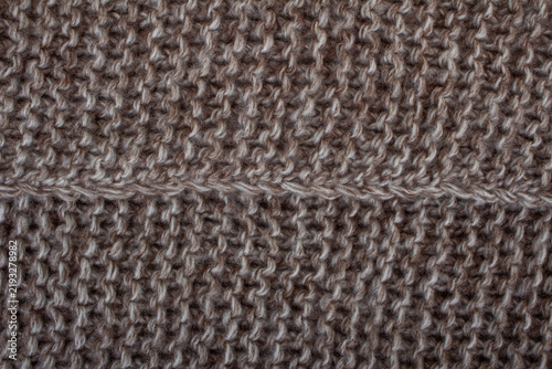 Fotografie Close-up texture of brown and beige knitted wool fabric with prominent seam line across the center