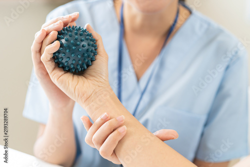 фотографія Close up of a physical therapist helping a patient exercise with a spiky massage ball for hand rehabilitation, occupational therapy and stroke recovery medical concept