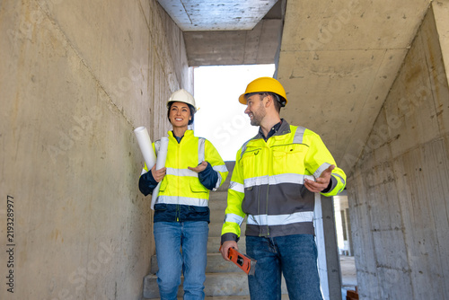 Fotografie Female and male engineers discussing project while walking downstairs