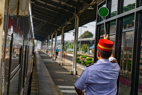 Fotografie A station master complete with his uniform and red hat is standing on platform w