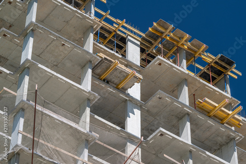 Foto Construction progresses on a towering building against a bright blue sky, showca