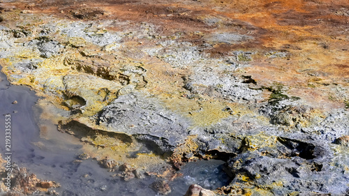 Fotografía Close-up of colorful geothermal ground at Kerlingarfjoll in Iceland, with sulfur-yellow and rust-orange mineral crusts surrounding a gray mud pool