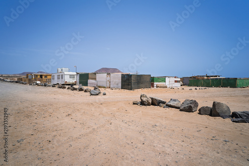 Konstfotografi Makeshift shacks and a caravan line the sandy edge of the informal settlement of El Jablito, Fuerteventura, Canary Islands, Spain
