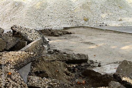 Foto Broken asphalt in the foreground transitions to a leveled road surface, with freshly laid gravel forming the background of an ongoing repair project