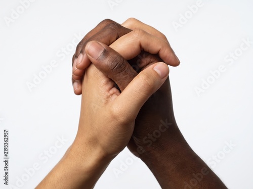 Close-up of two clasped hands with interlocked fingers on white backdrop