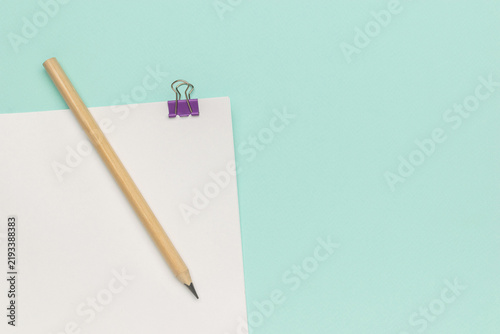 Minimalist Workspace with Pencil, Paper, and Purple Clip on Pastel Background