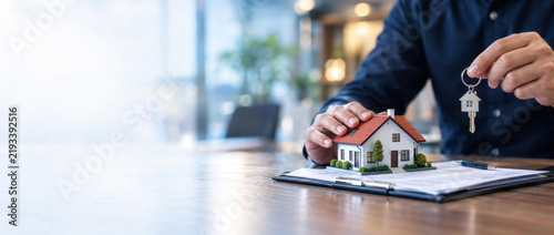 Keys to a Dream Home: A person holds a key, symbolizing ownership and the beginning of a new chapter, with a miniature house resting on a document.