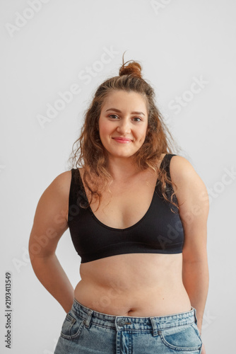Obraz na płótnie Woman in black top stands calmly and smiles without hiding her figure, confidence built after thirty five years, story many women recognise