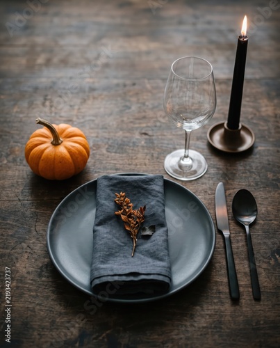 Elegant Halloween table setting with black plate, pumpkin, candle and rustic autumn decor