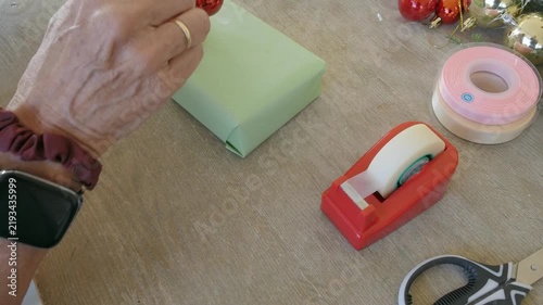 Woman's hands wrapping a christmas present with green paper