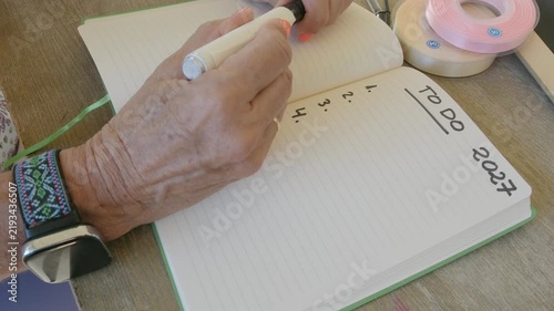 Elderly woman writing new year to do list for 2027