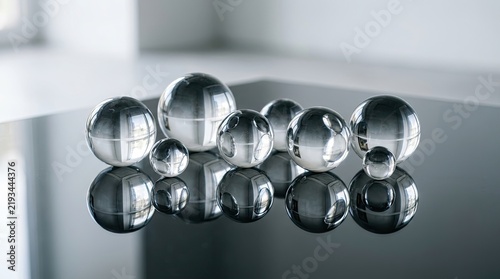 A collection of reflective glass spheres on a reflective surface.