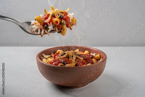 Koshary with rice, pasta, lentils, chickpeas, topped with fried onions. Concept of minimalistic dish highlighting flavors, textures. 