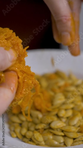 Pumpkin seed on plate. Female hand of housewife evaluates seed. Organic harvest, natural texture, and farming concept