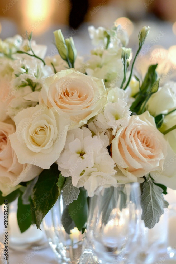 Fototapeta premium A vase filled with white flowers sits on a table. vertical frame