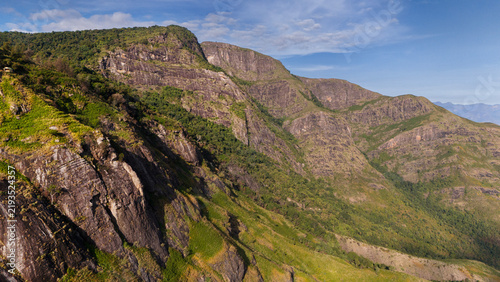 Wide aerial view of Kookal in the Palani Hills, Western Ghats, Tamil Nadu, overlooking shola forests, rolling grasslands, and layered monsoon clouds across a pristine lush highland landscape.