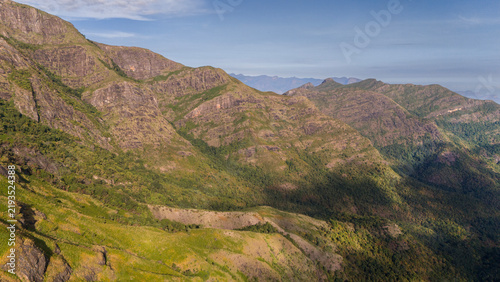 Wide aerial view of Kookal in the Palani Hills, Western Ghats, Tamil Nadu, overlooking shola forests, rolling grasslands, and layered monsoon clouds across a pristine lush highland landscape.