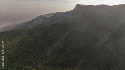 Wide aerial view of Kookal in the Palani Hills, Western Ghats, Tamil Nadu, overlooking shola forests, rolling grasslands, and layered monsoon clouds across a pristine lush highland landscape.