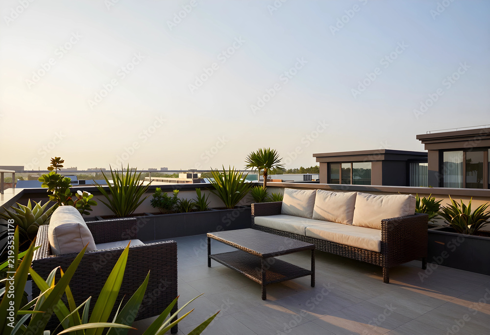 Fototapeta premium Luxury rooftop terrace lifestyle, modern outdoor lounge furniture with sofa and coffee table on a penthouse balcony at sunset for real estate marketing