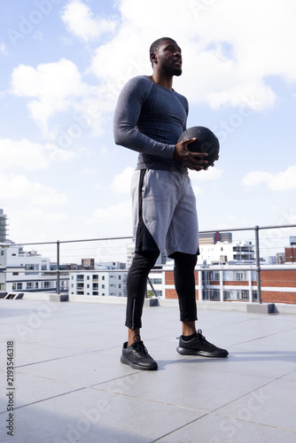 Cuadro en lienzo Man in 30s wearing gray compression top, leggings holding medicine ball by metal
