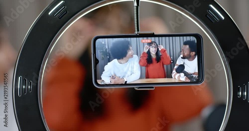 Diverse hosts seeing phone record light center host fixing specs others speaking into mic ringlight