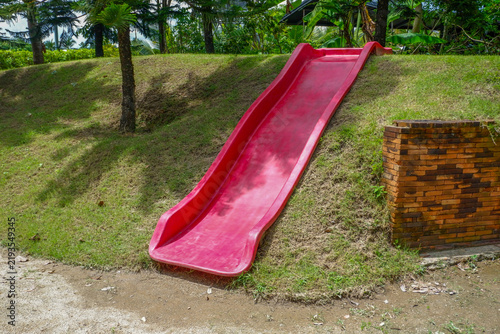 Playground slide with green grass in morning,Empty Outdoor playground,Children Play area in park or garden,Play yard,equipment,School yard, concept.