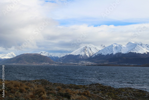 Quadro su tela Wide landscape shot of the snow-covered Andes mountain range seen across the dark waters of the Beagle Channel with tundra vegetation in the foreground in Ushuaia, Argentina