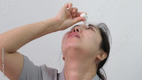 Woman applying prescribed eye drops during recovery after blepharoplasty. Postoperative eye care following eyelid surgery, including use of ophthalmic medication to support healing, prevent infection