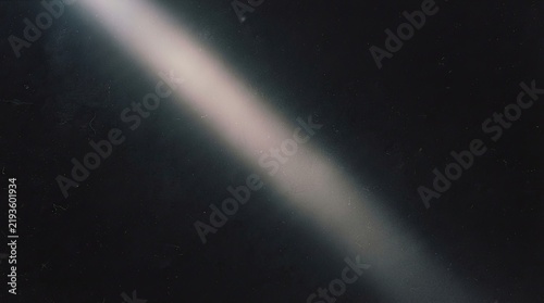 Diagonal beam of light on dark background with dust particles