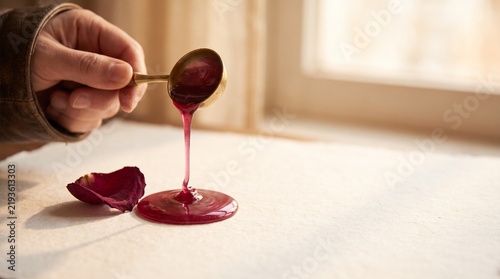 Pouring berry wax near a dried rose petal