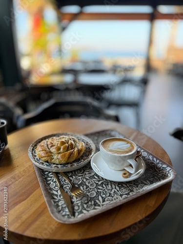 Morning coffee with pastry on a wooden table with a sea view in a cafe
