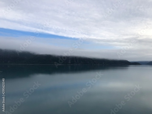Low Fog Layer Over Forested Coastline Reflecting on Calm Glacial Water, Glacier Bay Alaska