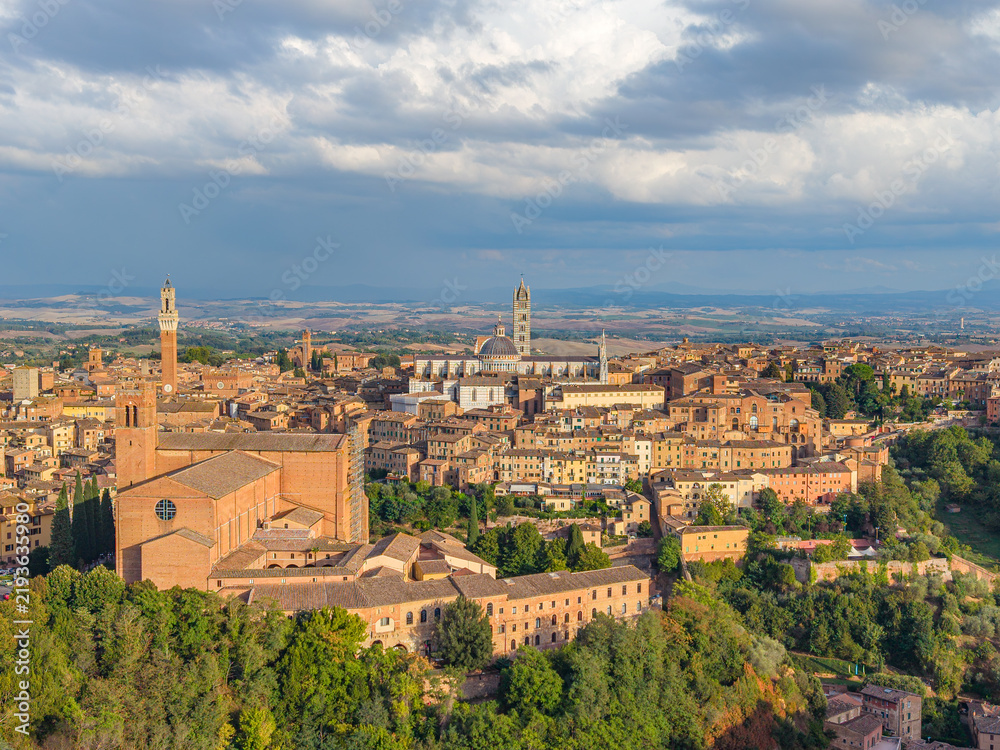 Obraz premium Aerial view of the Italian famouse city Siena with the landmarks of Basilica di San Domenico, Piazza del Campo tower and Duomo di Siena standing out over the old town center