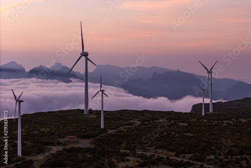 Wind turbines on elevated terrain above cloud cover in Madeira, decarbonization and energy transition concept