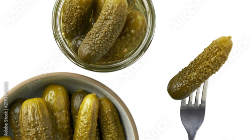 Fotografie Isolated gherkins and pickles in glass jar, ceramic bowl, and one on a metal for
