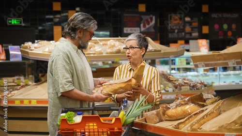 Mature couple choosing fresh bread together in a supermarket bakery