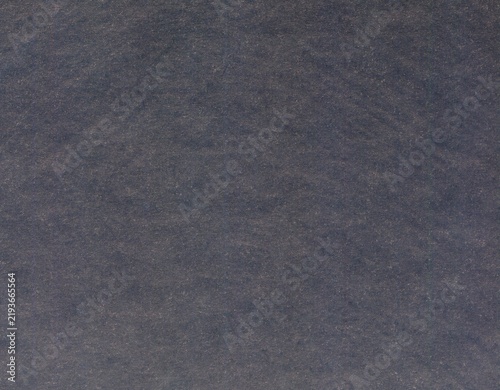 Greyish, rough and a little bit dusty textured surface of cardboard, background, texture. Backdrop of faded grey paper surface. Old and shabby paper piece. Ancient wall in ashen color. Gray covering